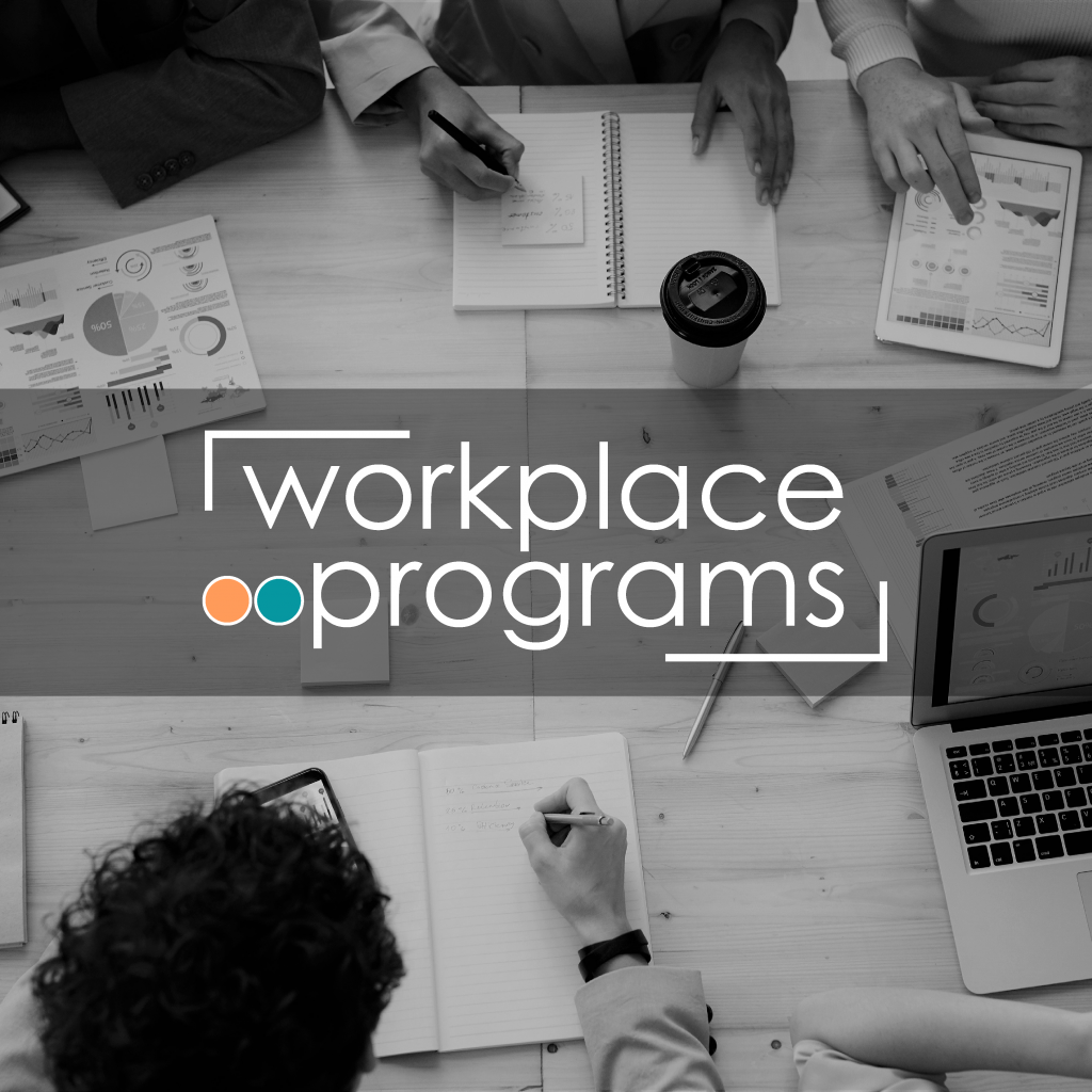 A picture of people at a table writing in notebooks, text overlay reads, "Workplace programs"